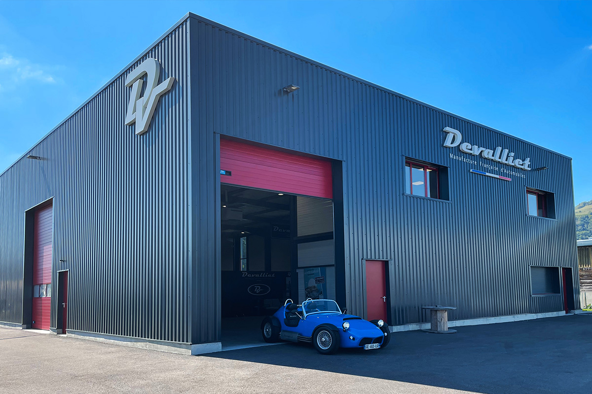 Image du bâtiment Devalliet avec porte de garage ouverte et modèle Mugello 375F bleu garé devant