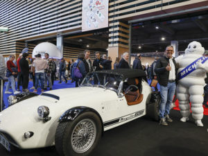 Mugello 375 F blanche avec Hervé Valliet à sa roite faisant une accolade au bonhomme Michelin lors du salon Époqu'Auto 2023